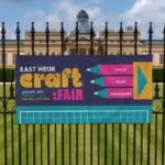 Backdrop Banners: Printed craft fair banner on black railings in front of a park