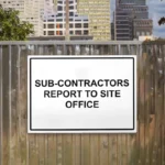 Sub-Contractors Report to Site Office Sign: Sub Contractors Report to Site Office Sign shown on a timber site hoarding